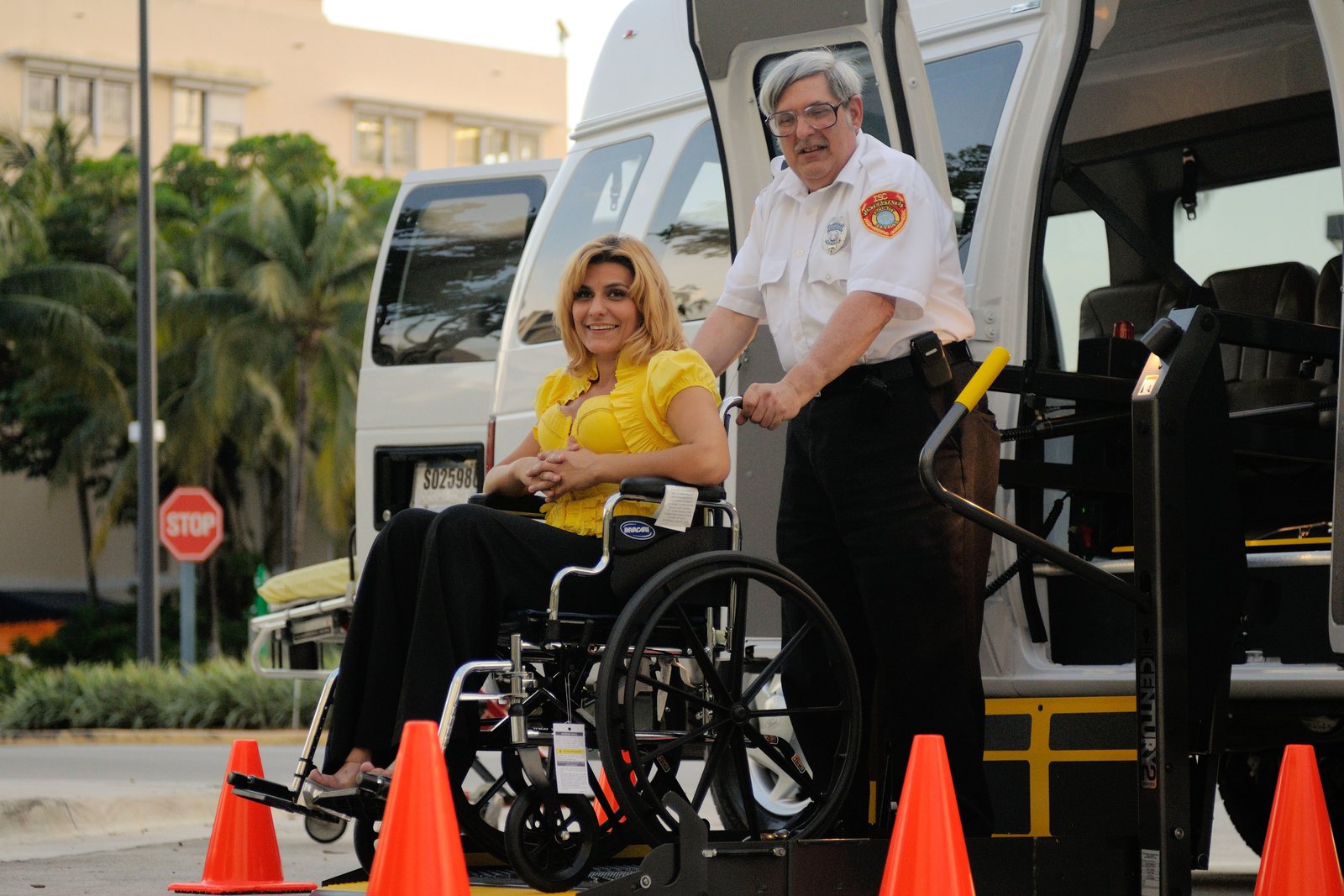 A wheelchair user receiving assistance beside a wheelchair-accessible non-emergency transport van